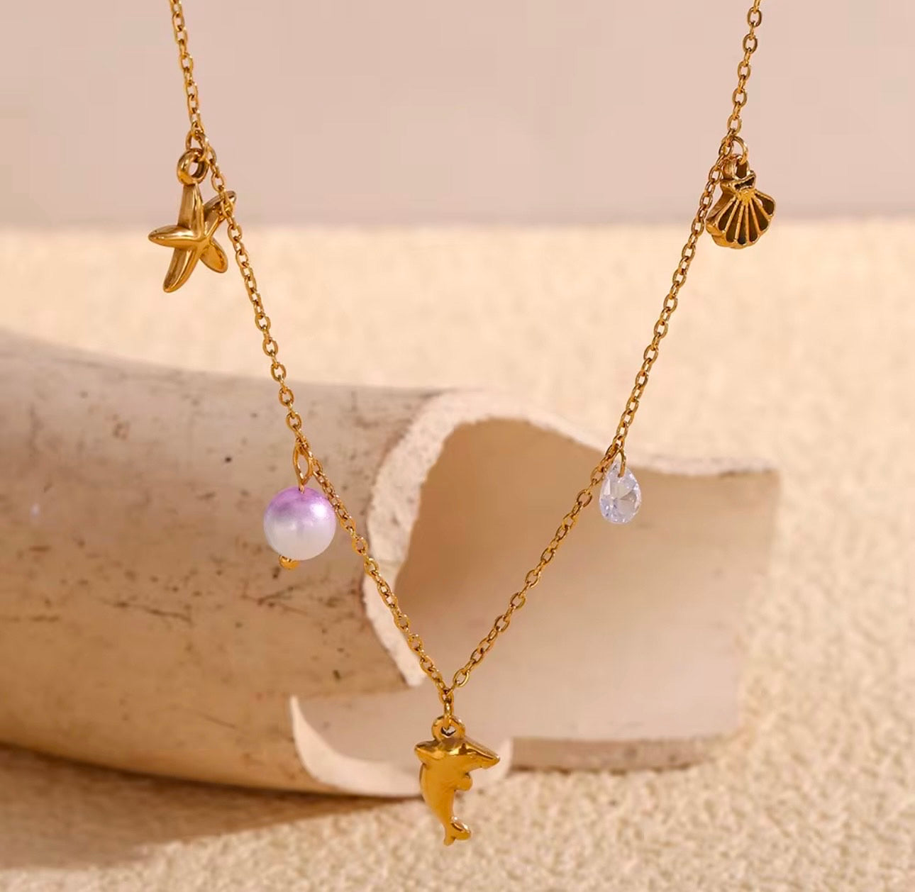 Collar con Charm, estrella, perla, delfín, diamante y concha.